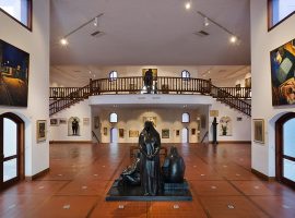 תצלום של מוזיאון ראלי מבפנים: מסדרון רחב ידיים המוביל אל חדר גדול ממנו. במרכז המסדרון פסל של כמה דמויות.