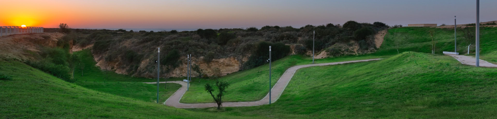אזור גבעות נמוכות מכוסה דשא, ושביל הליכה מתפתל עובר בו, ולצידו עמודי תאורה. בחלק המרוחק של התמונה ניתן לראות שטח גבעות דומה ללא דשא, אלא מכוסה צמחייה טבעית.