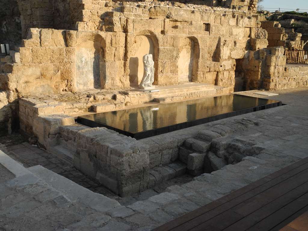 הנימפאון הרומי -מבנה חלקי עתיק על שפת בריכת מים ובחזיתו פסל חסר ראש של אישה