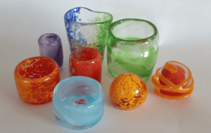 יצירות זכוכית צבעוניות ובהן כוסות וצנצנות קטנות פתוחות