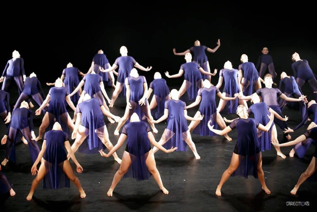 מחול ובו רקדניות רבות לבושות בבגד גוף סגול מקשתות את גבן לאחור ומושיטות ידיים לצדדים