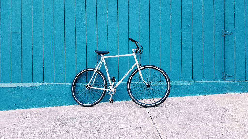 אופניים שעונים על גדר עץ כחולה