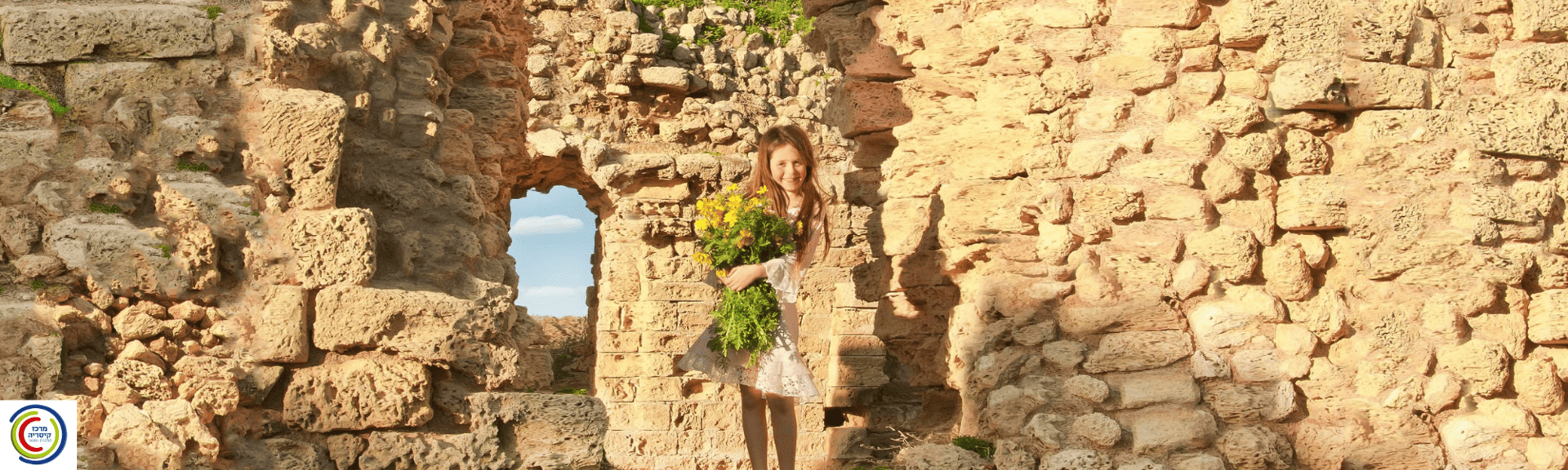 ילדה אוחזת זר פרחי בר צהובים על רקע קירות אבן עתיקים