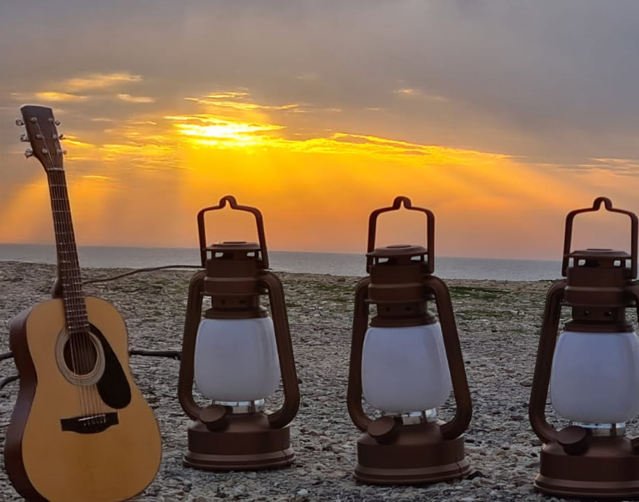 עששיות וגיטרה על רקע הים בשקיעה