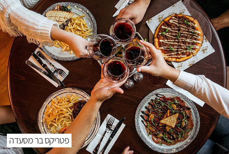שולחן עם אוכל ומשקאות, אנשים מחזיקים כוסות יין לחגיגה מ.