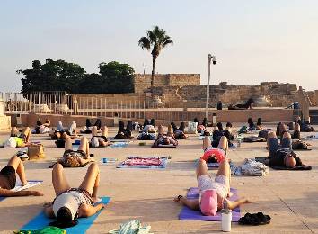שיעור יוגה על גג עם נוף לים וקיסריה העתיקה.